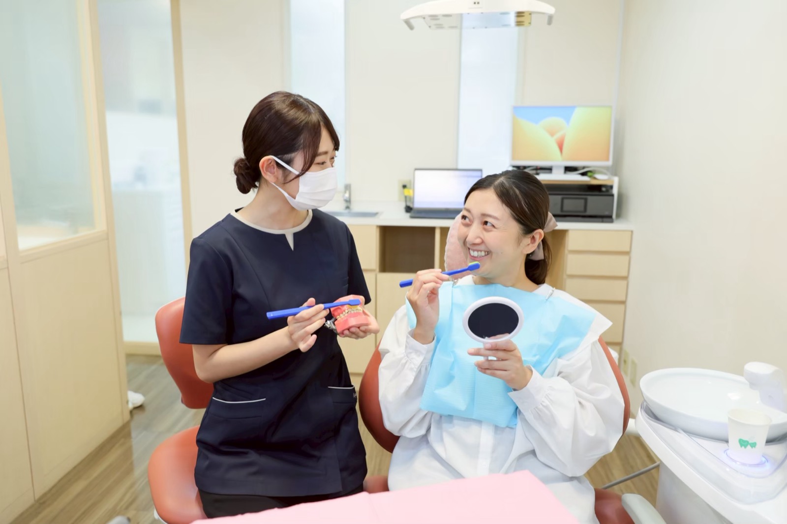 Higienista dental explicando a escovação com um modelo de dentes